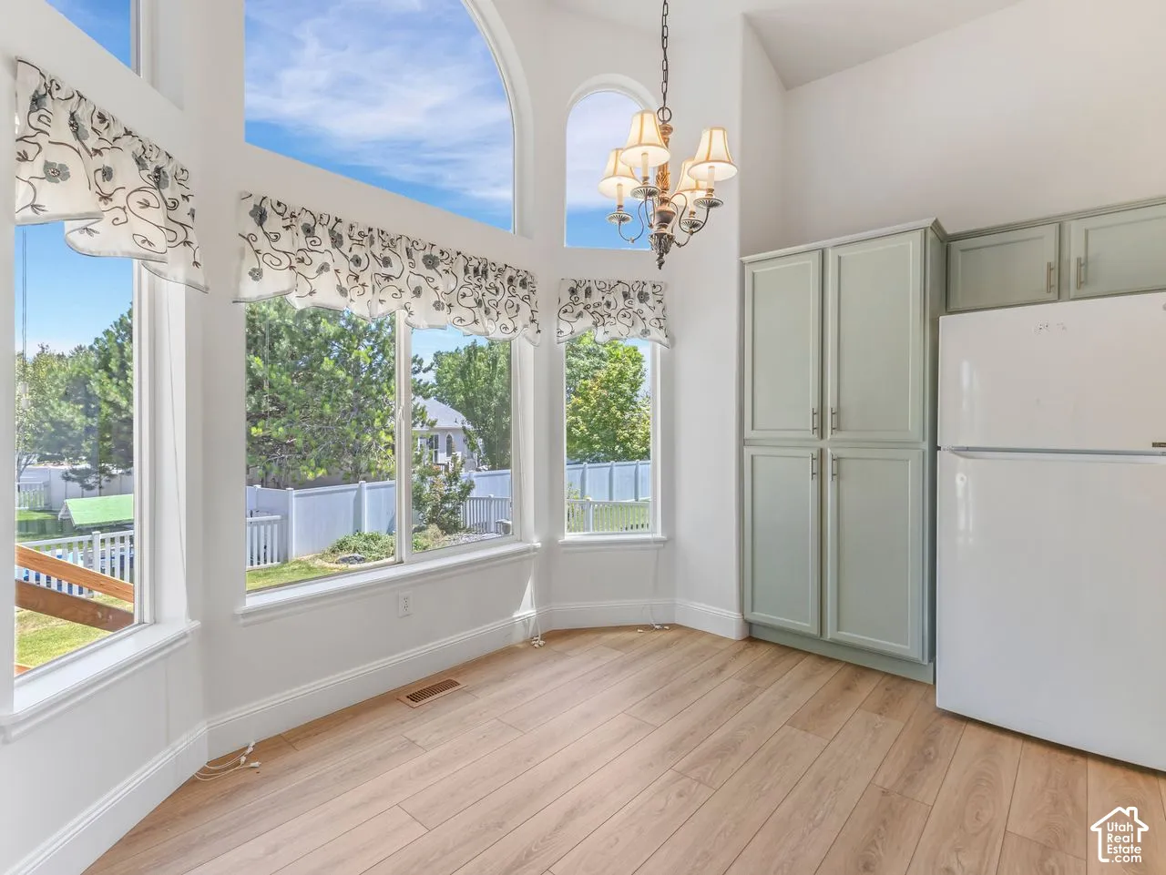 Vaulted ceilings featuring an arched window, wood-finish flooring, and light green cabinetry