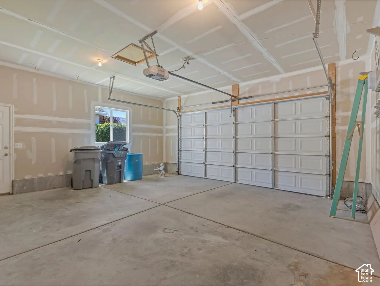 Spacious garage featuring a concrete floor, overhead lighting, a segmented garage door, and a single window