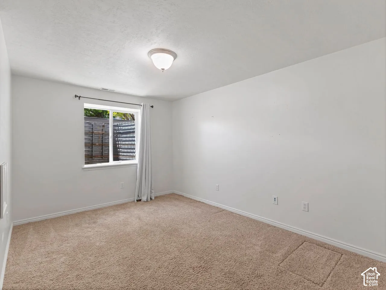 Carpeted room featuring a single window with white trim, a flush-mount ceiling light fixture, and white painted walls