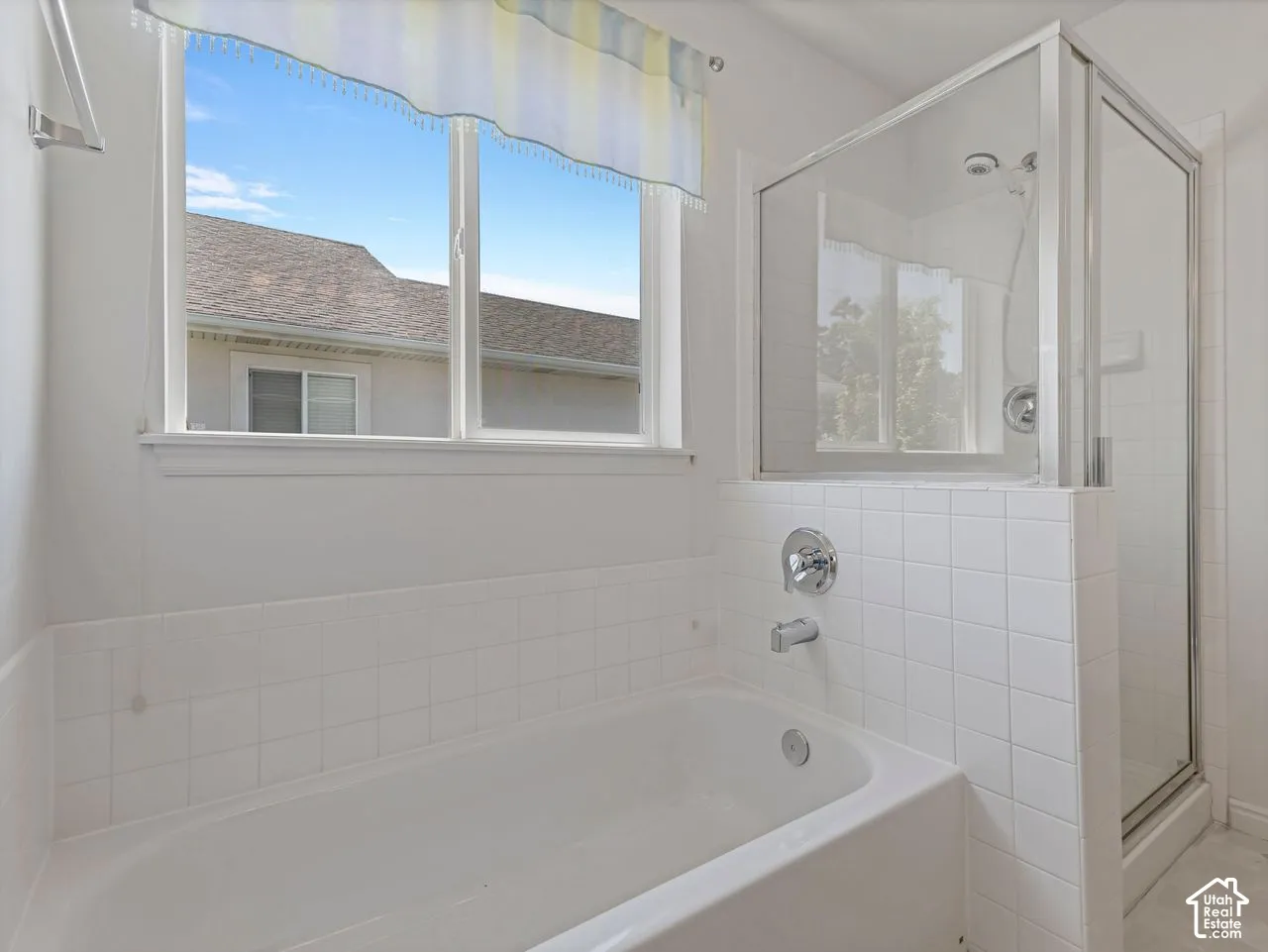 White ceramic subway tile surrounds a built-in bathtub with chrome fixtures