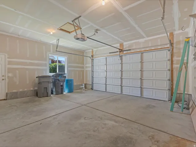 Spacious garage featuring a concrete floor, overhead lighting, a segmented garage door, and a single window