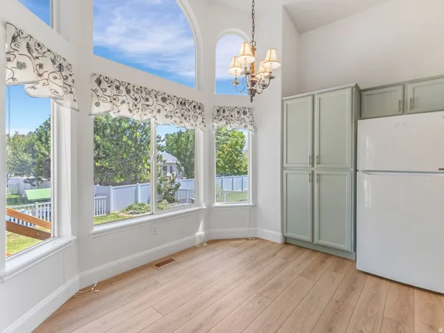 Vaulted ceilings featuring an arched window, wood-finish flooring, and light green cabinetry