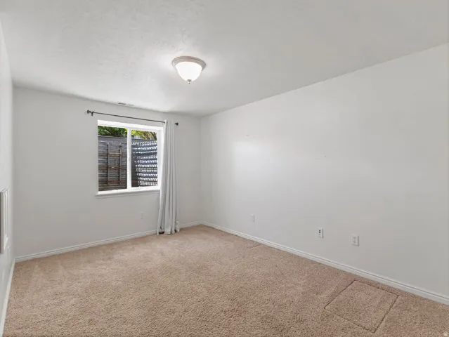 Carpeted room featuring a single window with white trim, a flush-mount ceiling light fixture, and white painted walls