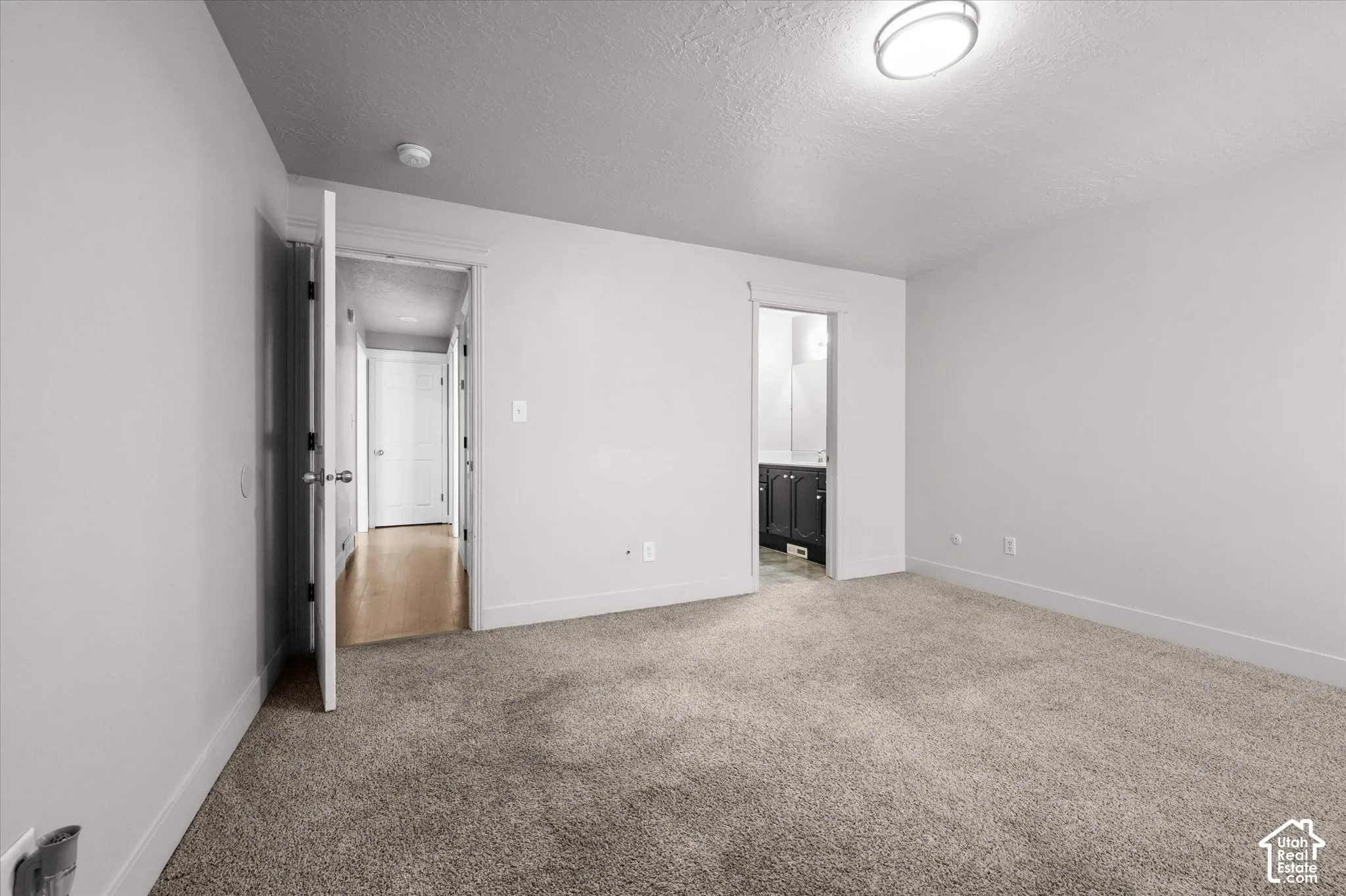 Spacious carpeted bedroom featuring clean white walls, recessed ceiling lighting, and dual mirrored closet doors with frameless hardware