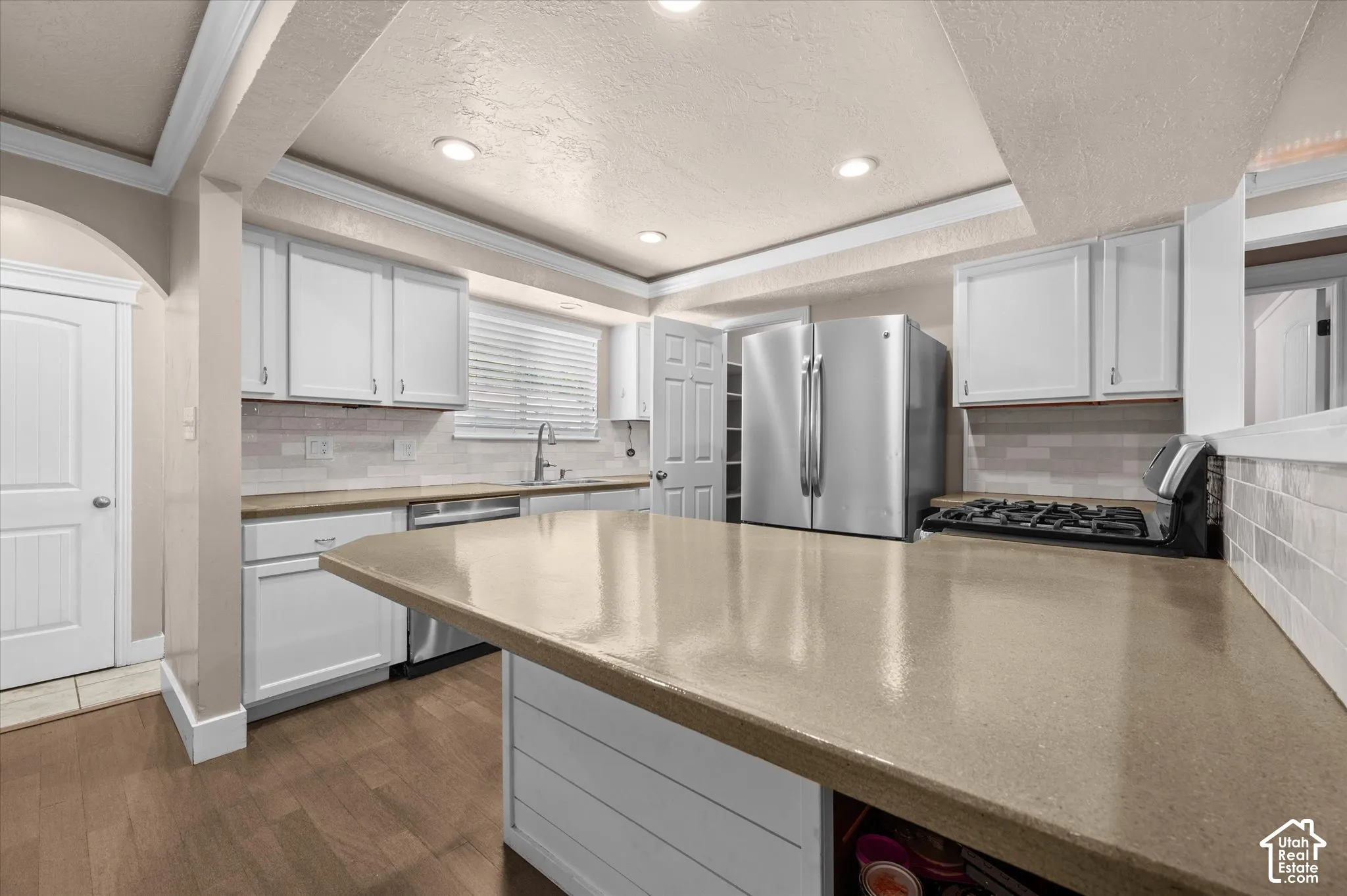 Kitchen featuring an expansive center island, white shaker cabinetry, stainless steel appliances, and wood-finish flooring