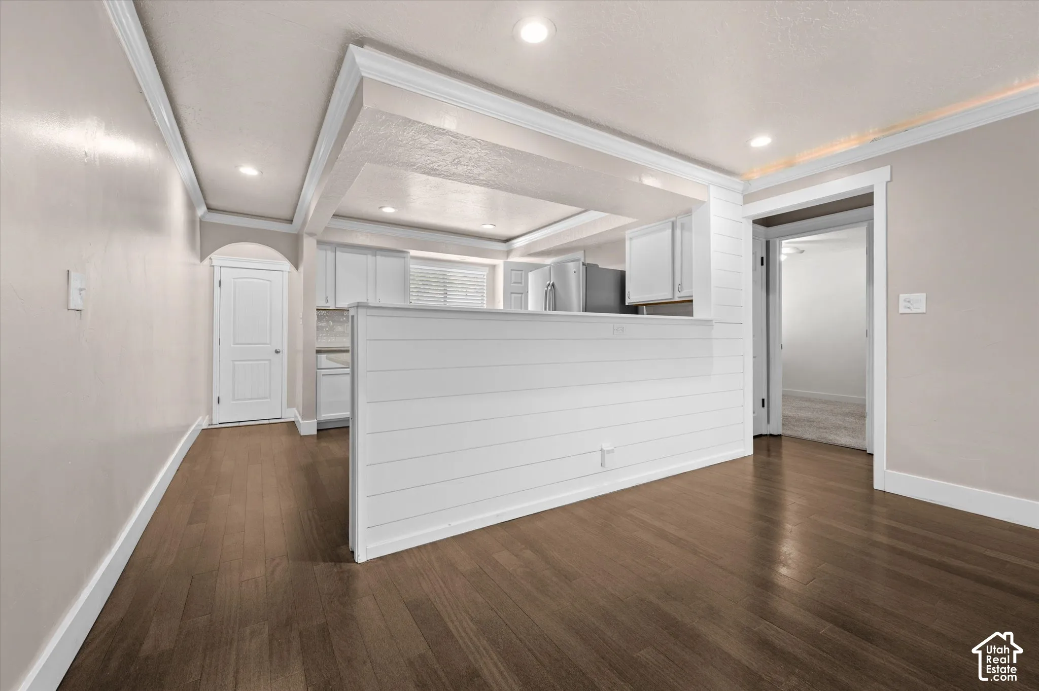 Wood-finish flooring throughout, white baseboards, crown molding, recessed lighting, and a shiplap-paneled half-wall