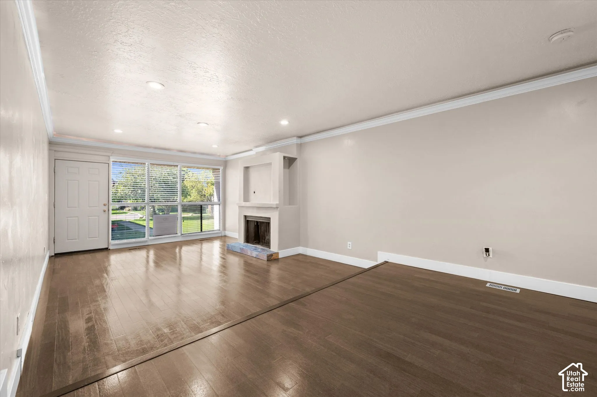 Wood-finish flooring, built-in fireplace, large picture windows, recessed lighting, and crown molding