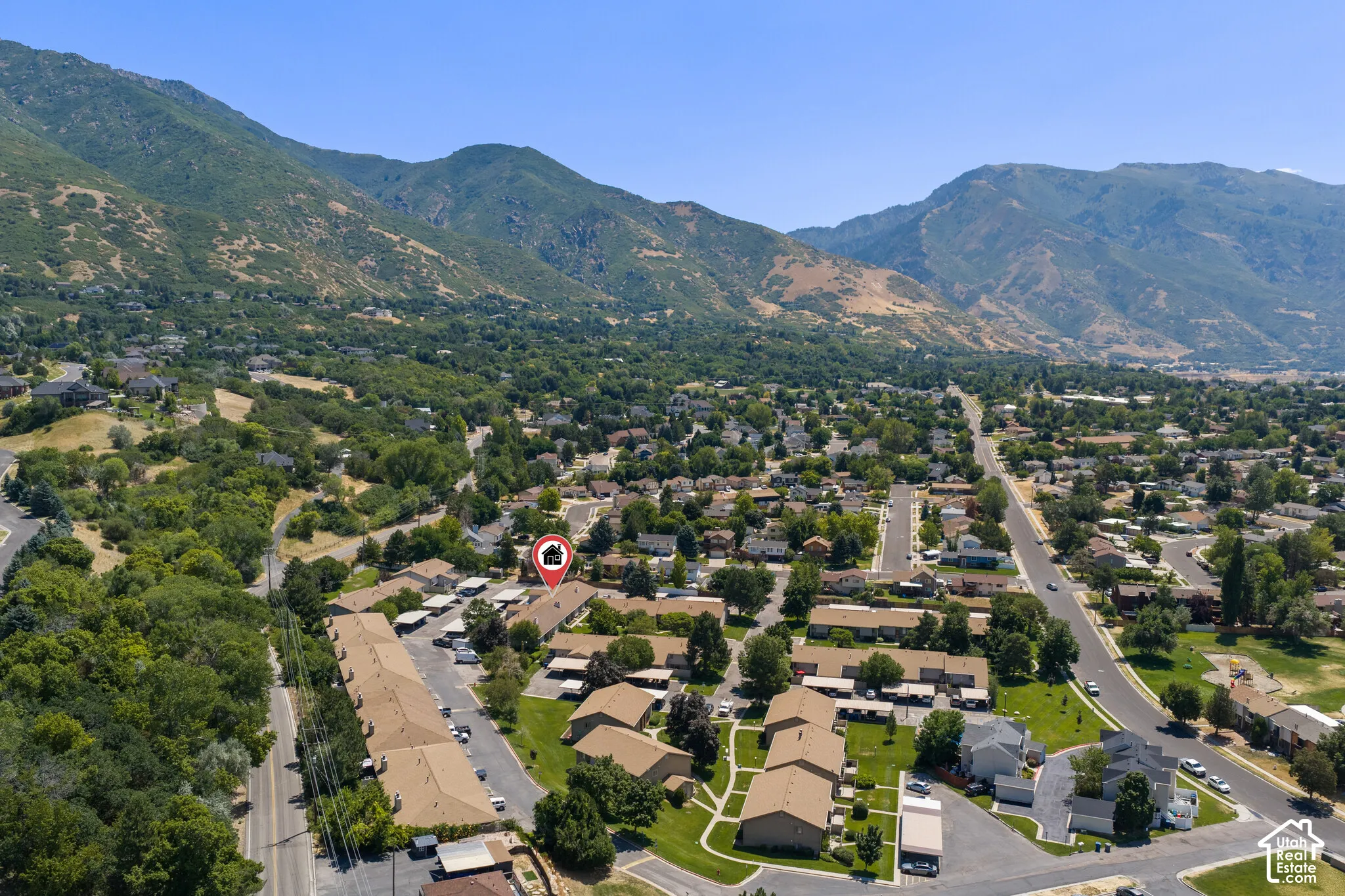 Aerial perspective highlighting a residential community with abundant mature trees and mountainous terrain