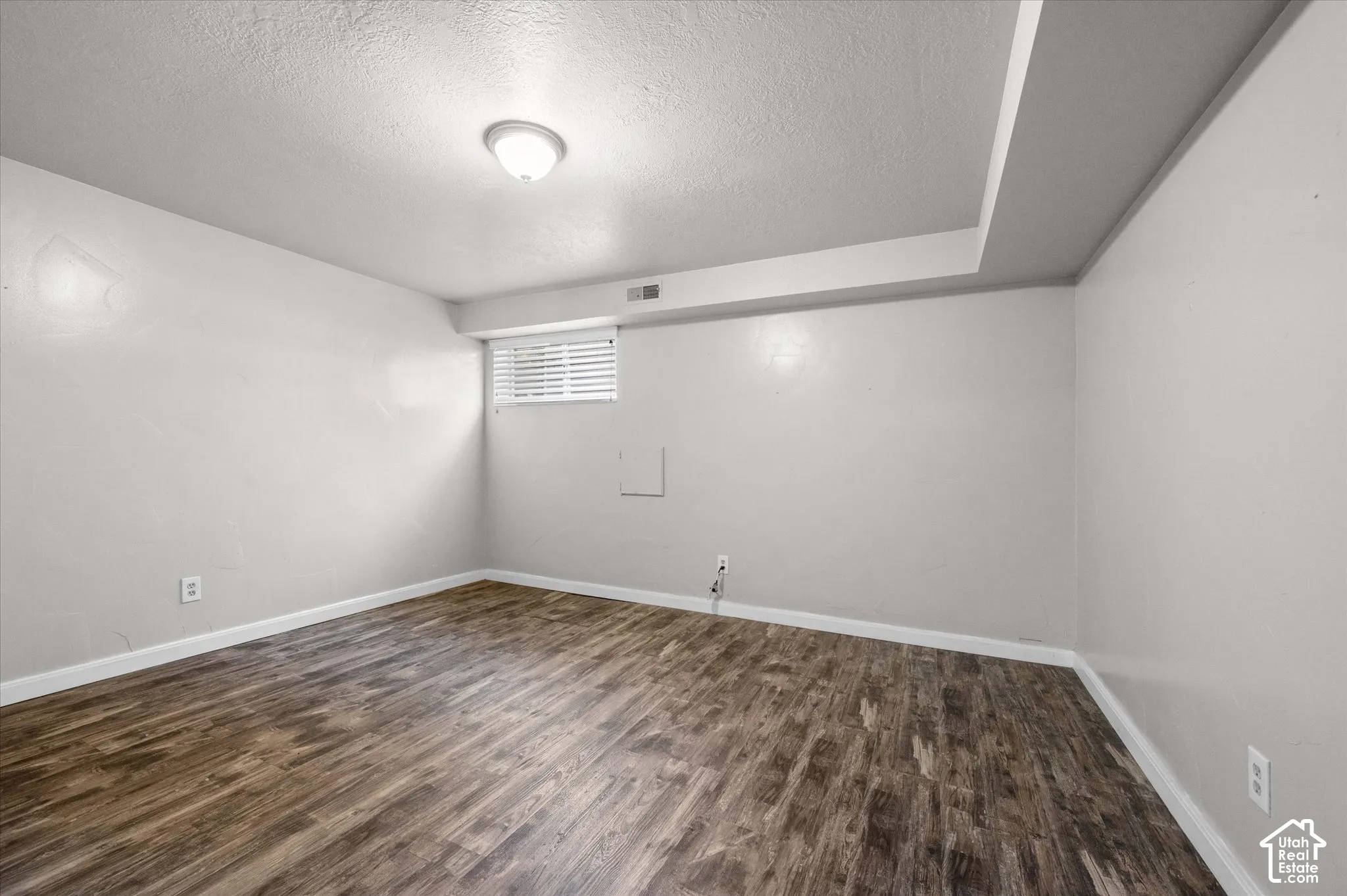 Spacious room featuring wood-finish flooring, recessed ceiling lighting, and fresh white walls