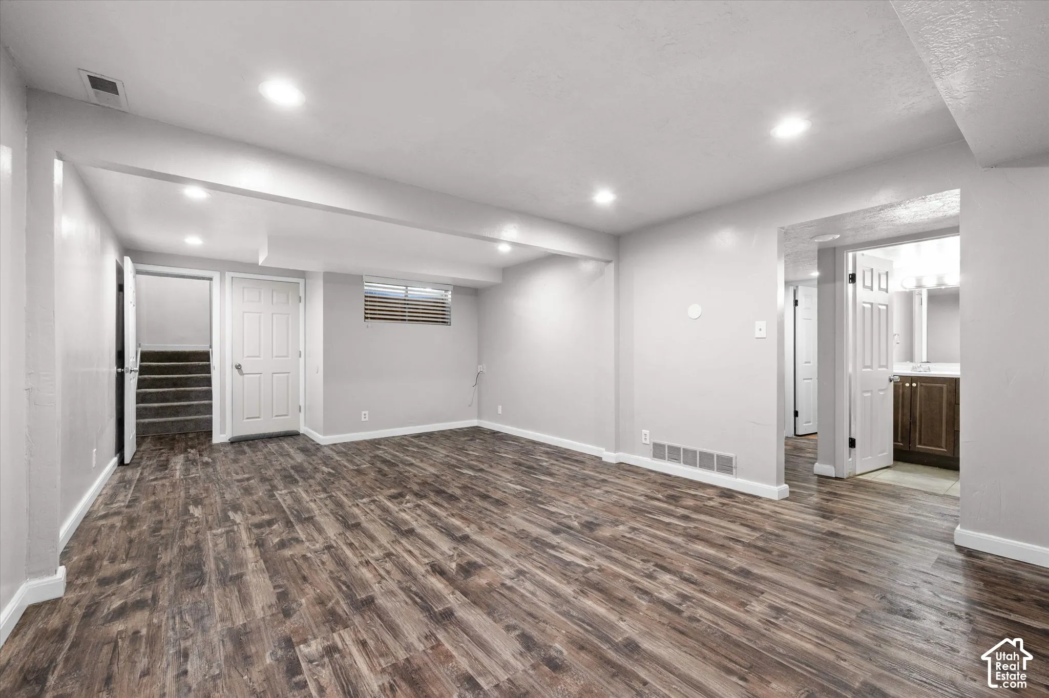 Spacious room with wood-finish flooring, recessed lighting, and light gray wall finishes