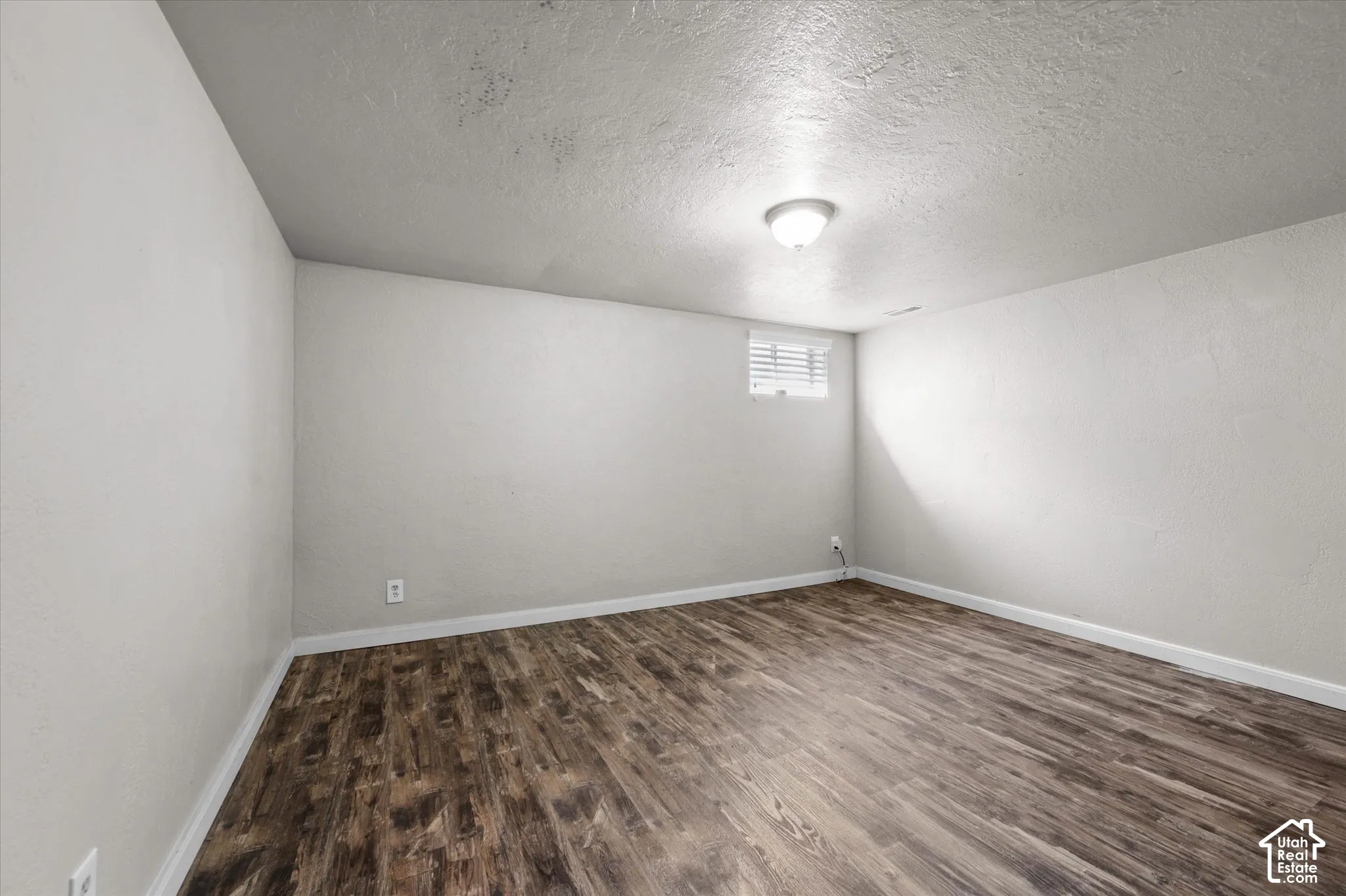 Wood-finish flooring, white painted walls, and a single flush-mount ceiling light