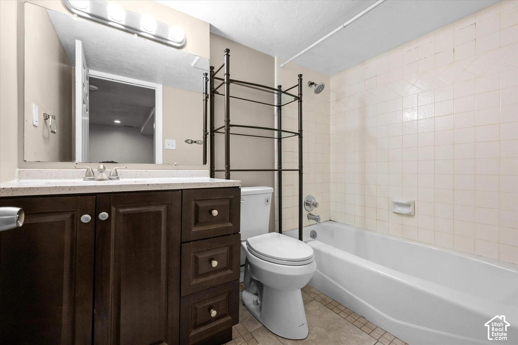 Vanity with dark wood-finish cabinetry, light-toned countertop, and chrome fixtures
