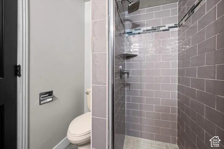 Glass-enclosed shower with gray subway tile surround and a tiled accent band