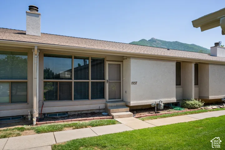 Exterior elevation featuring a stucco finish, multi-pane windows, and a paved walkway