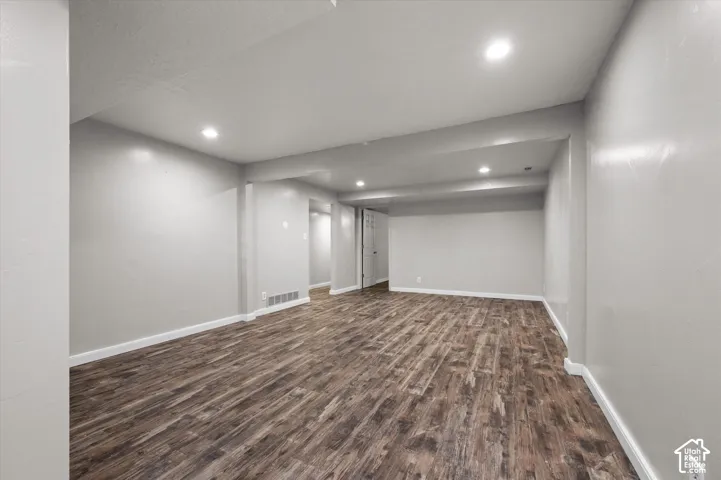 Spacious room featuring wood-finish flooring, recessed lighting, and light-toned walls