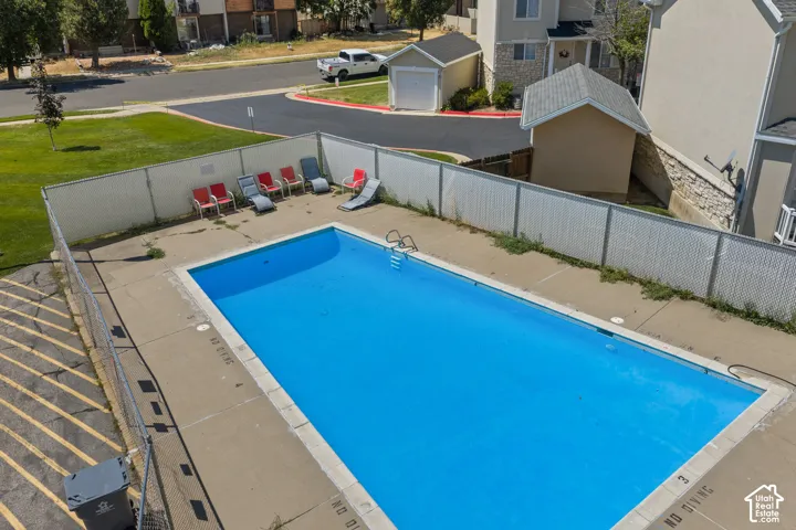 Outdoor swimming pool with concrete decking, surrounding privacy fencing, and a nearby manicured lawn area