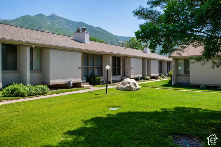 Manicured green lawn with a large decorative boulder and a walkway leading to multiple units