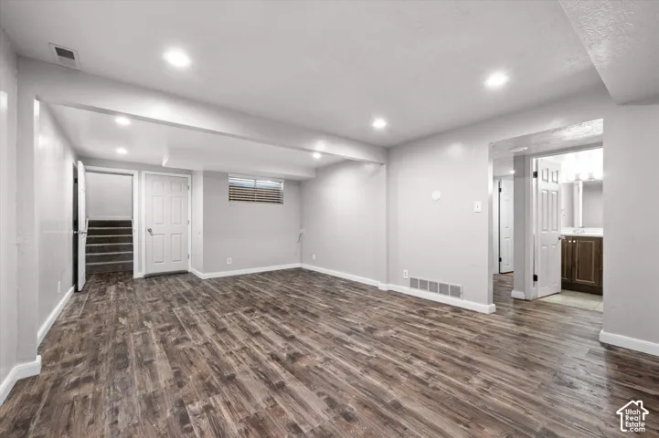 Spacious room with wood-finish flooring, recessed lighting, and light gray wall finishes