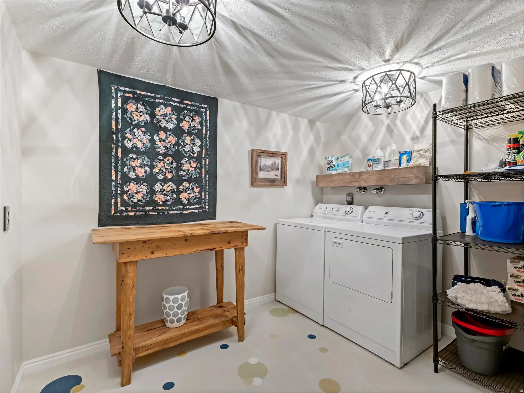 Dedicated laundry area featuring a floating wood shelf, patterned flooring, and overhead lighting fixtures