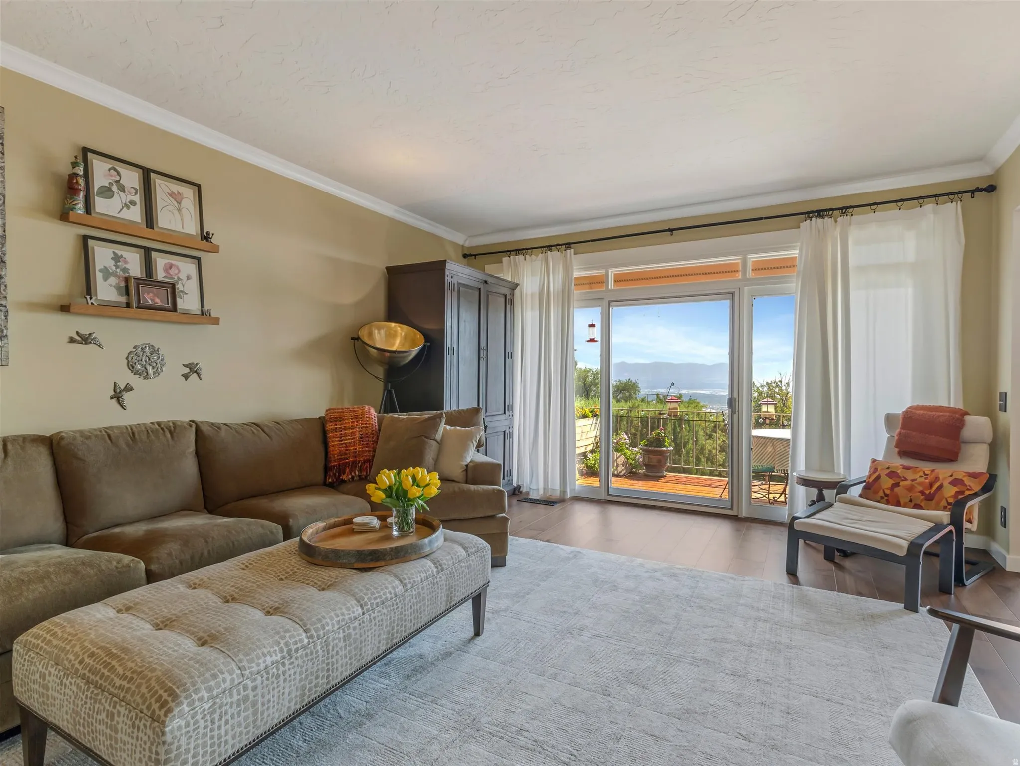 Spacious living area featuring large sliding glass doors, crown molding, wood-finish flooring, and a broad outdoor balcony