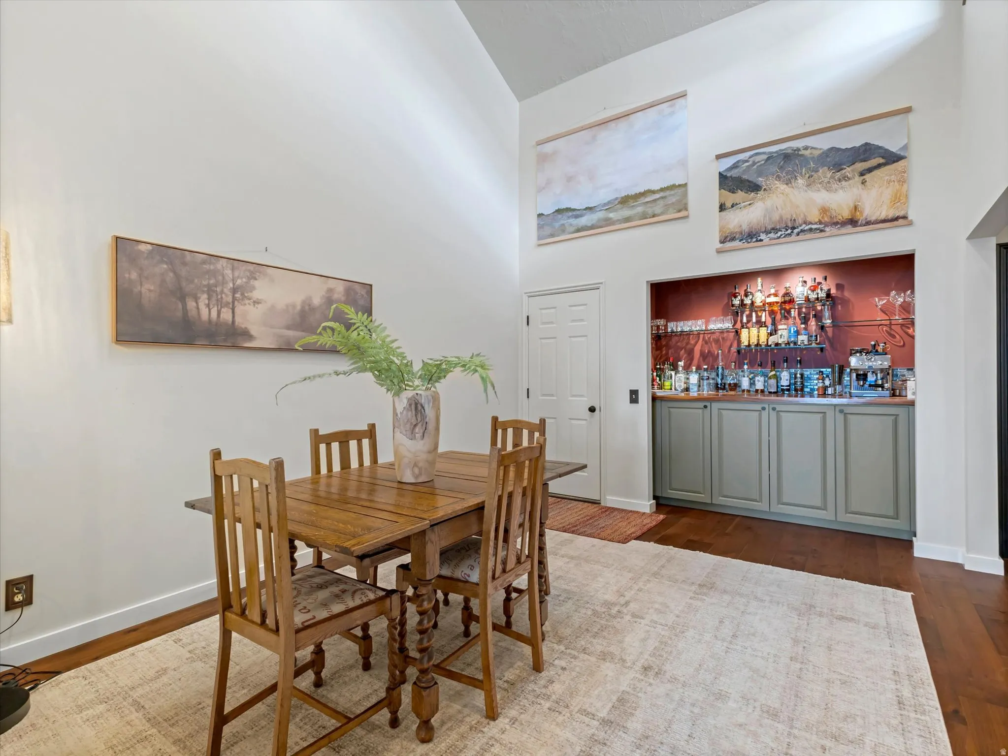 Dining area featuring vaulted ceilings, wood-finish flooring, and a built-in beverage bar with cabinetry