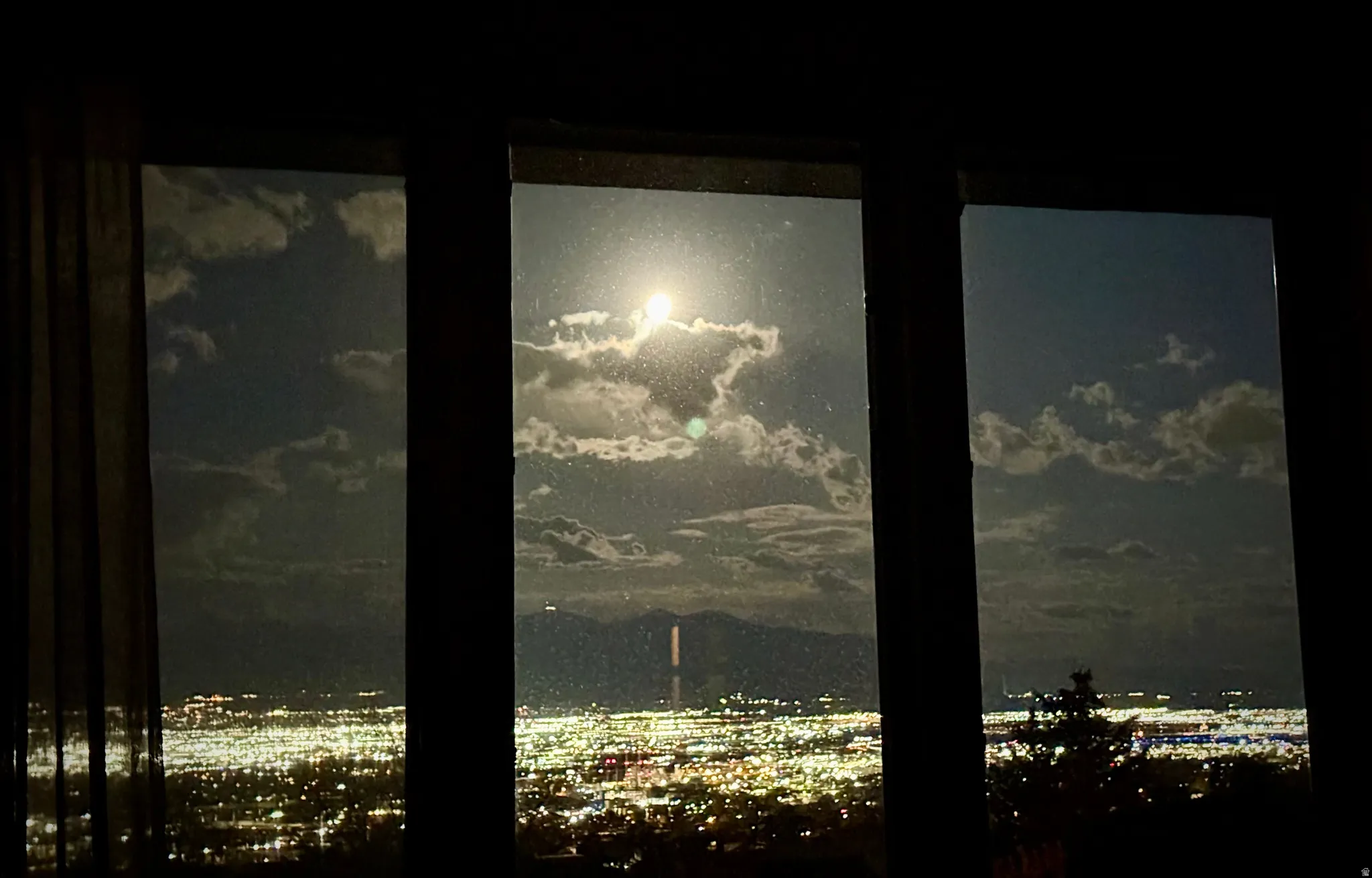 Expansive window offering a panoramic view of the distant city lights and mountainous landscape