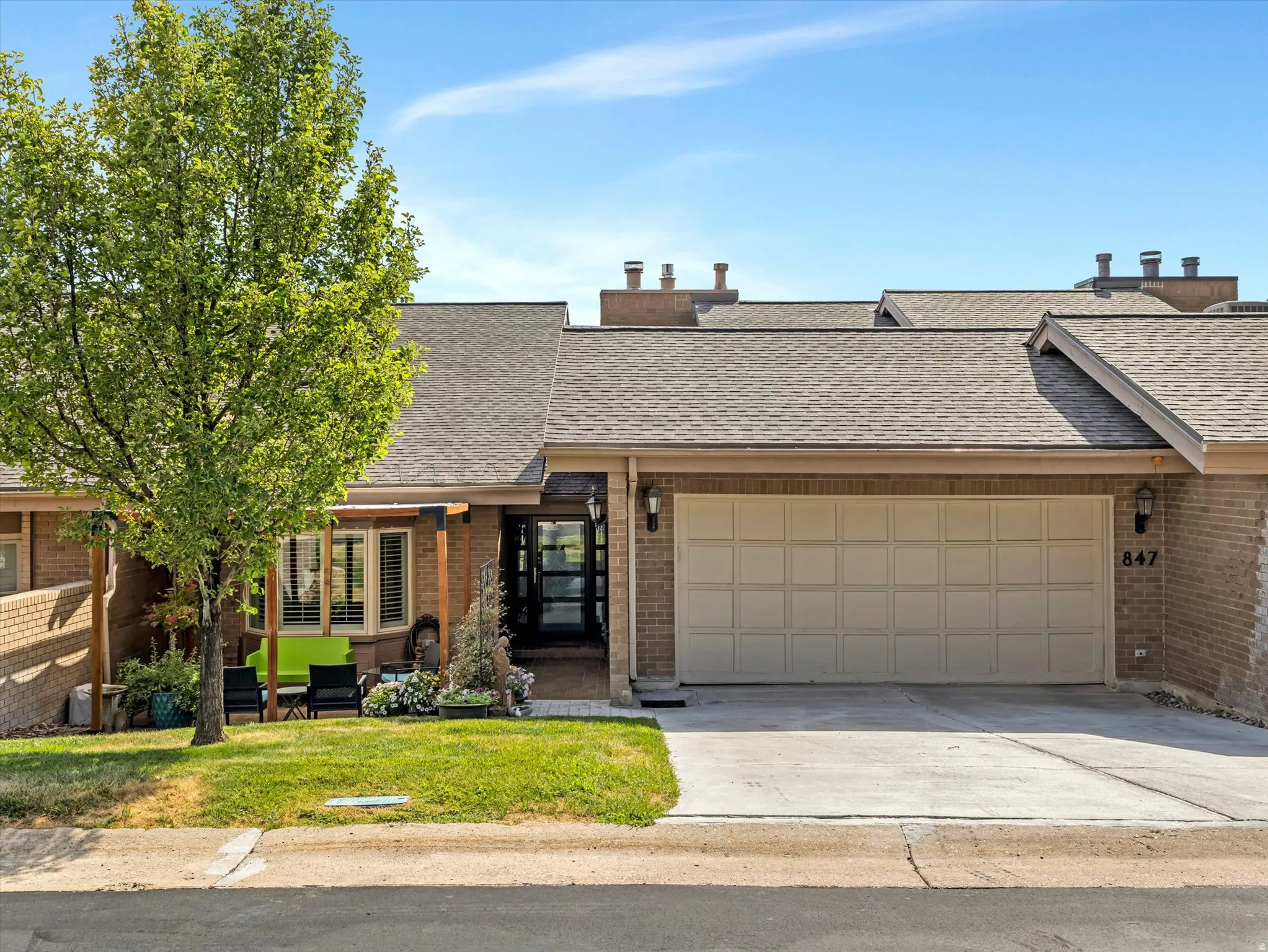 Brick exterior with an attached two-car garage, featuring a glass-paneled entry door and a covered front patio