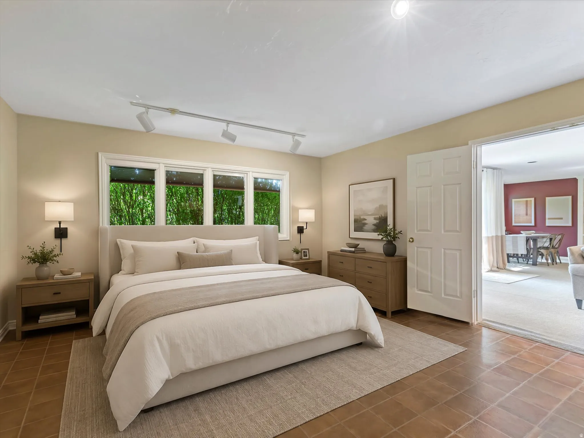 Spacious room with large windows overlooking greenery, featuring track lighting and recessed lighting