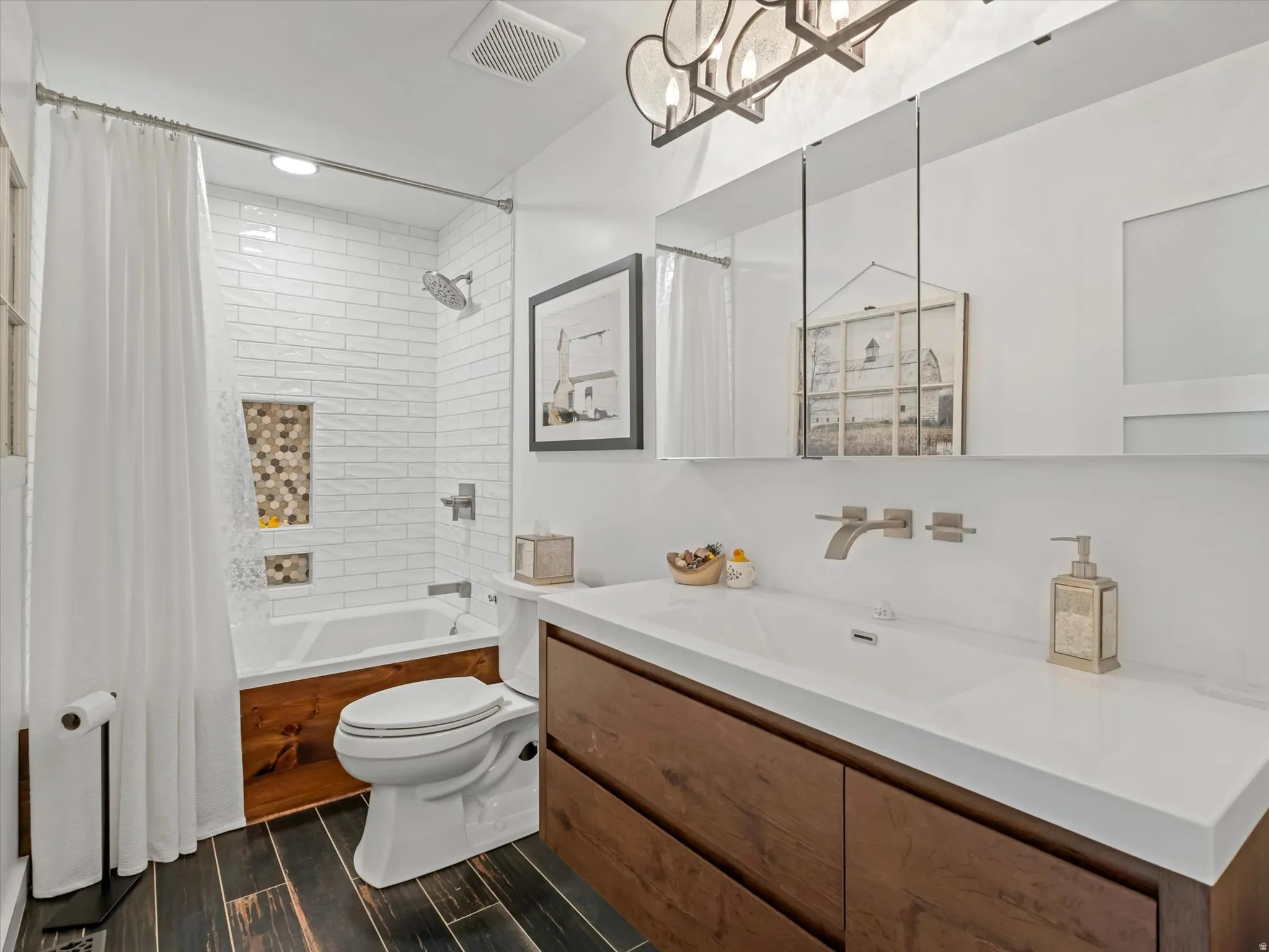 Modern bathroom featuring dark wood-finish flooring, a white subway tile shower surround with a mosaic accent niche, a deep soaking tub with wood paneling, a wall-mounted vanity faucet, and a contemporary light fixture