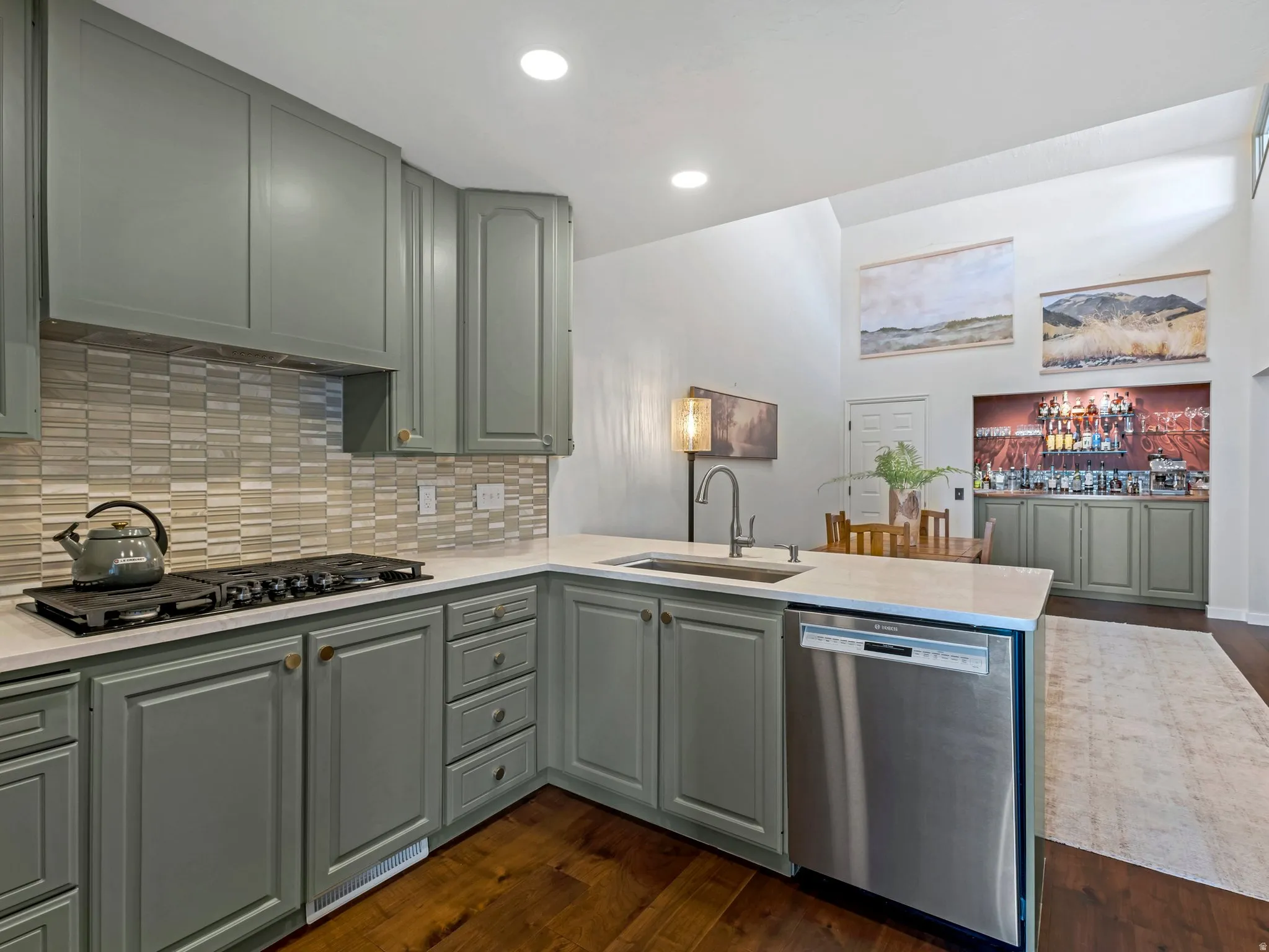 Kitchen with light green cabinetry, integrated stainless steel dishwasher, and a gas cooktop