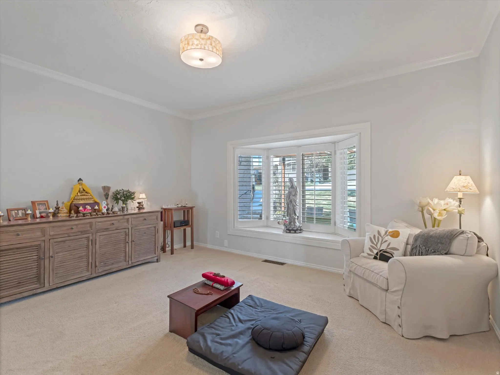 Recessed bay window with interior plantation shutters, crown molding, a semi-flush mount ceiling fixture, and neutral carpet flooring