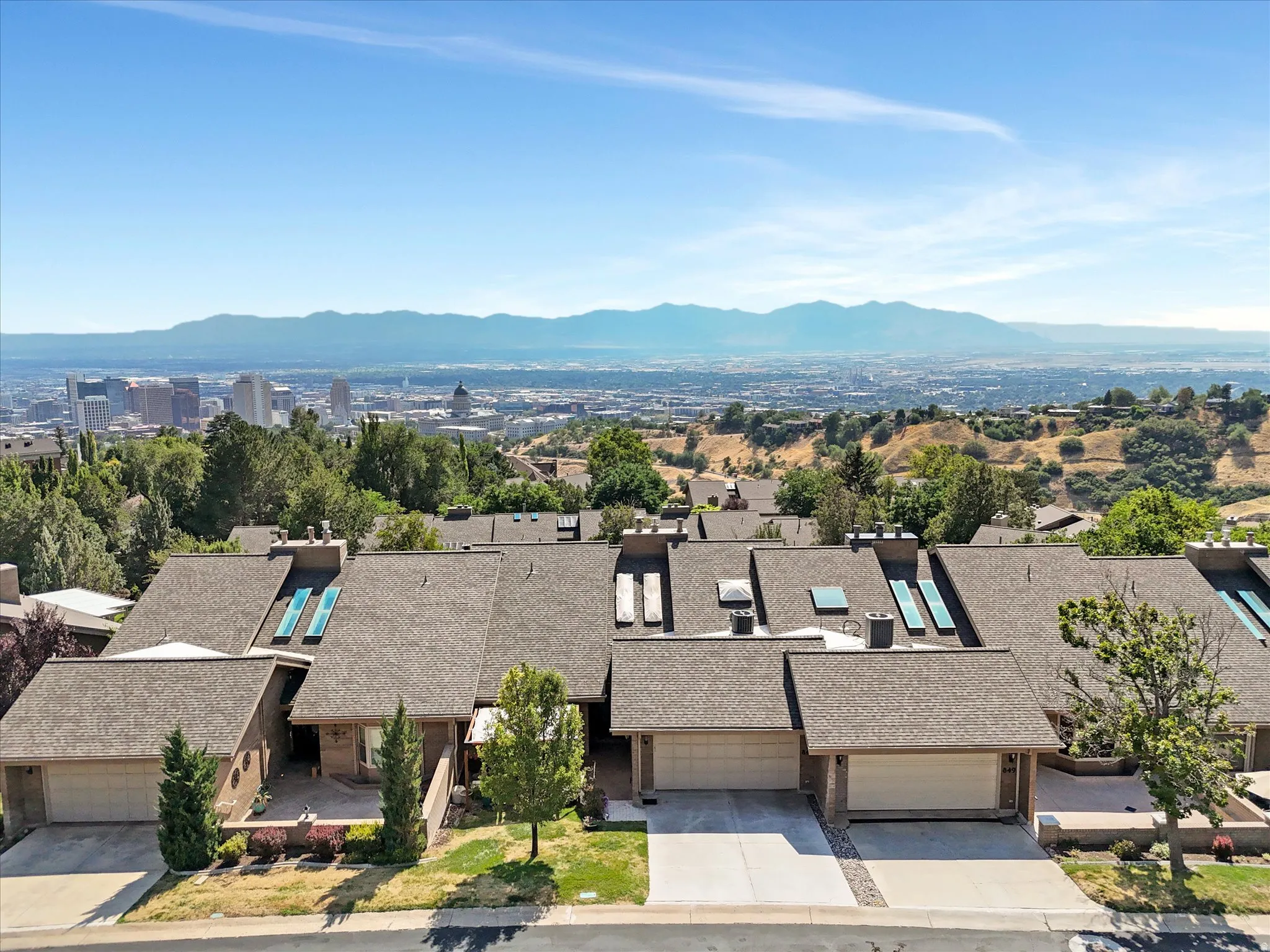 Terraced row of homes featuring attached garages, skylights, and a composite shingle roof