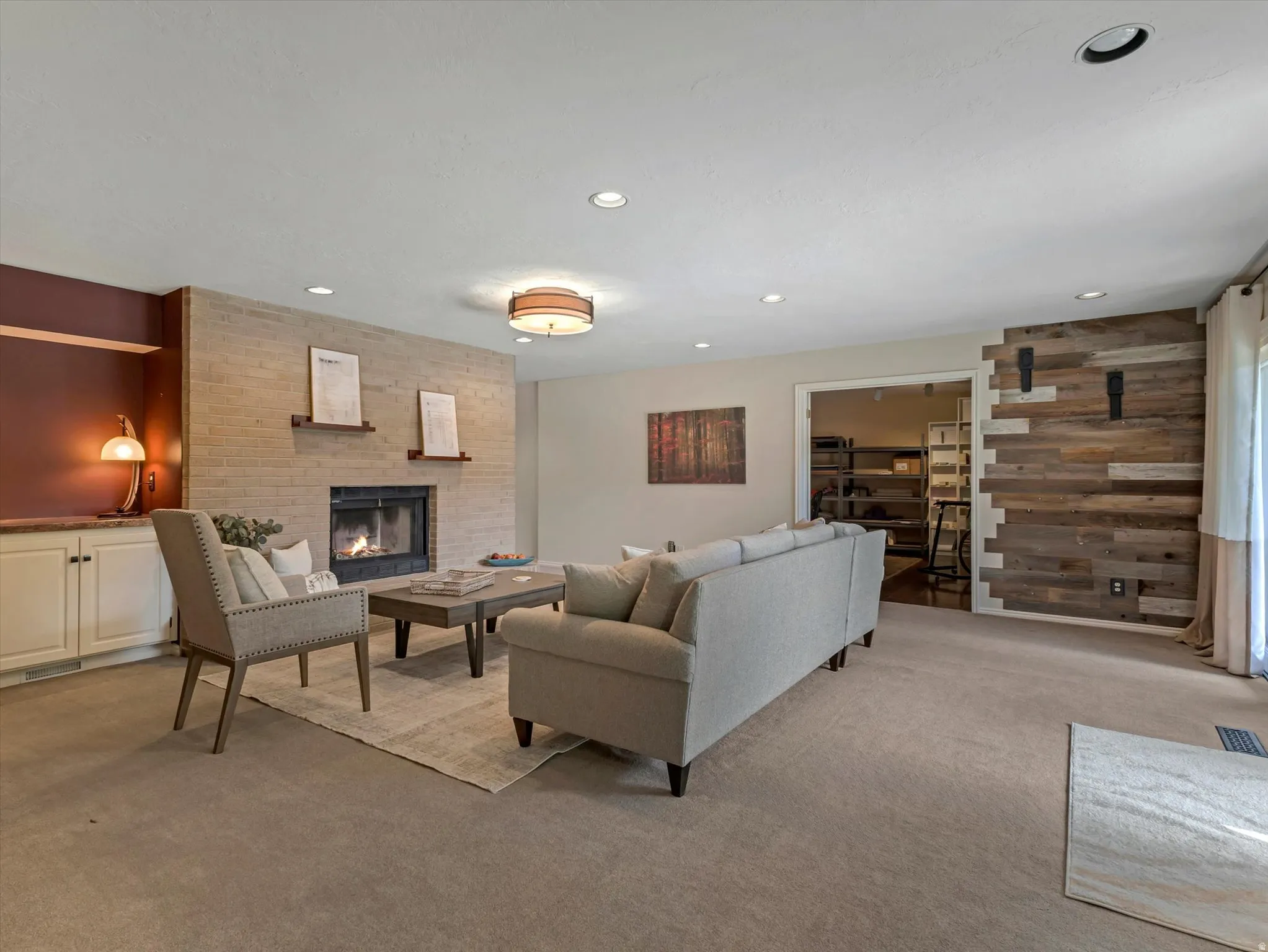 Living area featuring a brick fireplace, built-in shelving, recessed lighting, and a wood-paneled accent wall