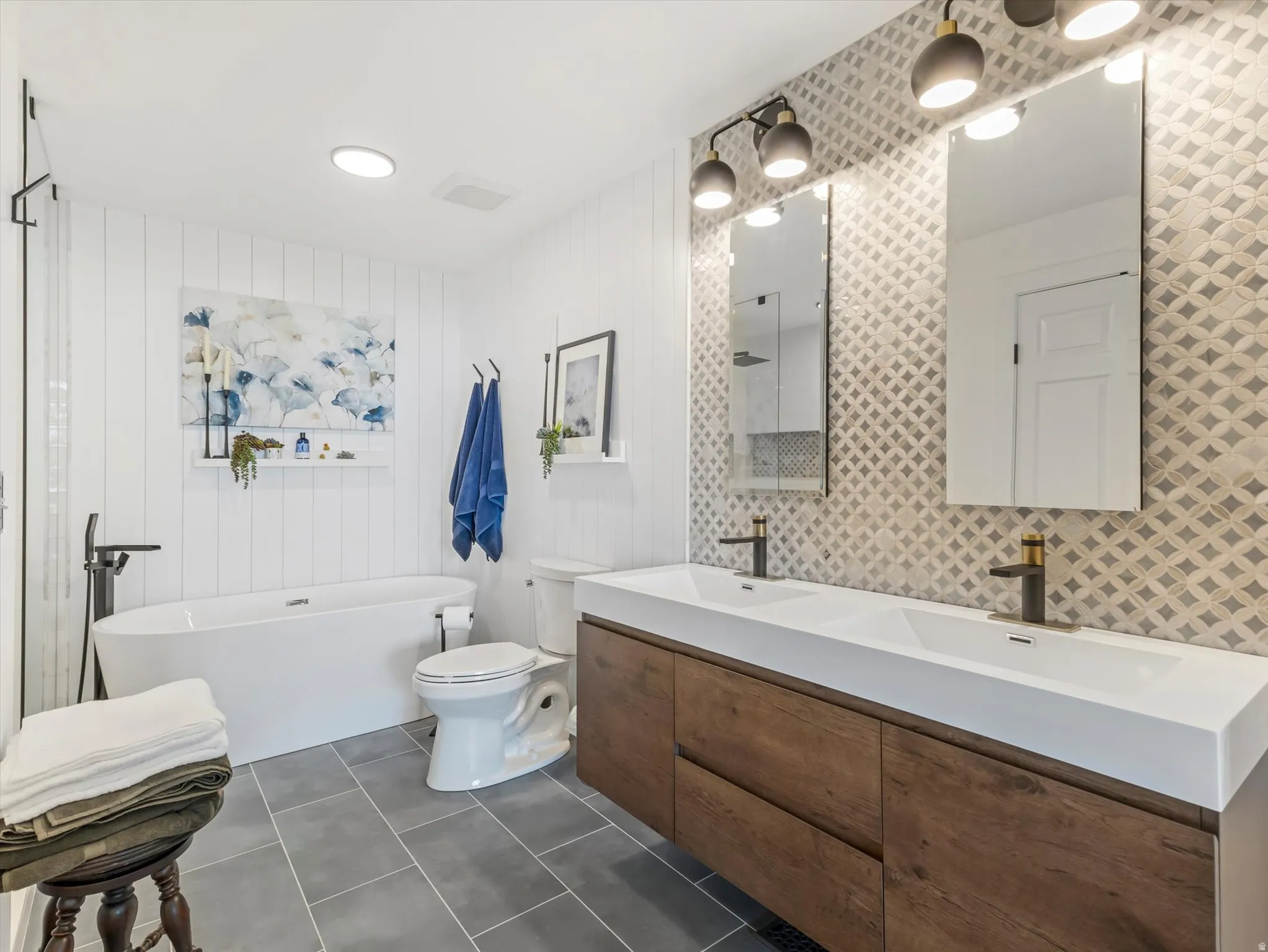 Dual vanity with white integral sinks and bronze-finish faucets, set against a geometric patterned tile wall