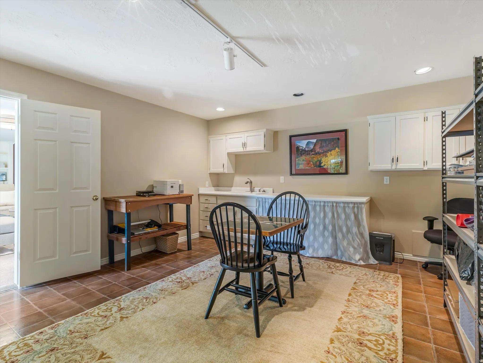 Versatile room featuring tile flooring, white cabinetry, and a countertop with an integrated sink