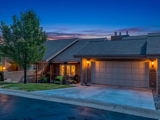 Brick facade with a multi-paneled garage door, exposed aggregate driveway, and exterior wall sconces