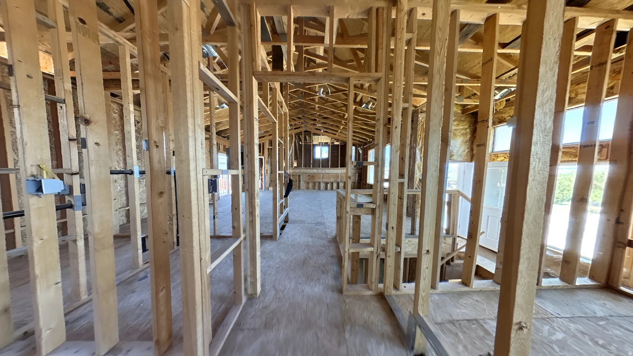 Interior framing showcasing a plywood subfloor, exposed wooden studs, and visible ceiling joists