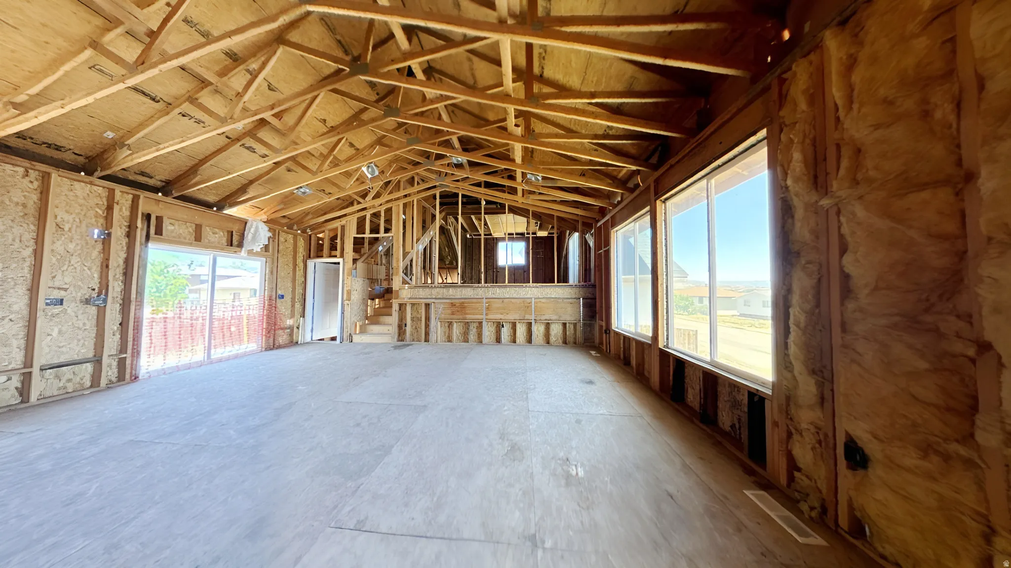 Spacious interior framing with exposed rafters and plywood subflooring