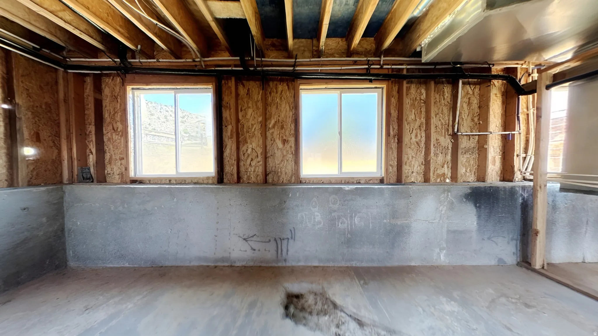 Unfinished interior space featuring a concrete foundation, exposed wood framing, and two sliding windows