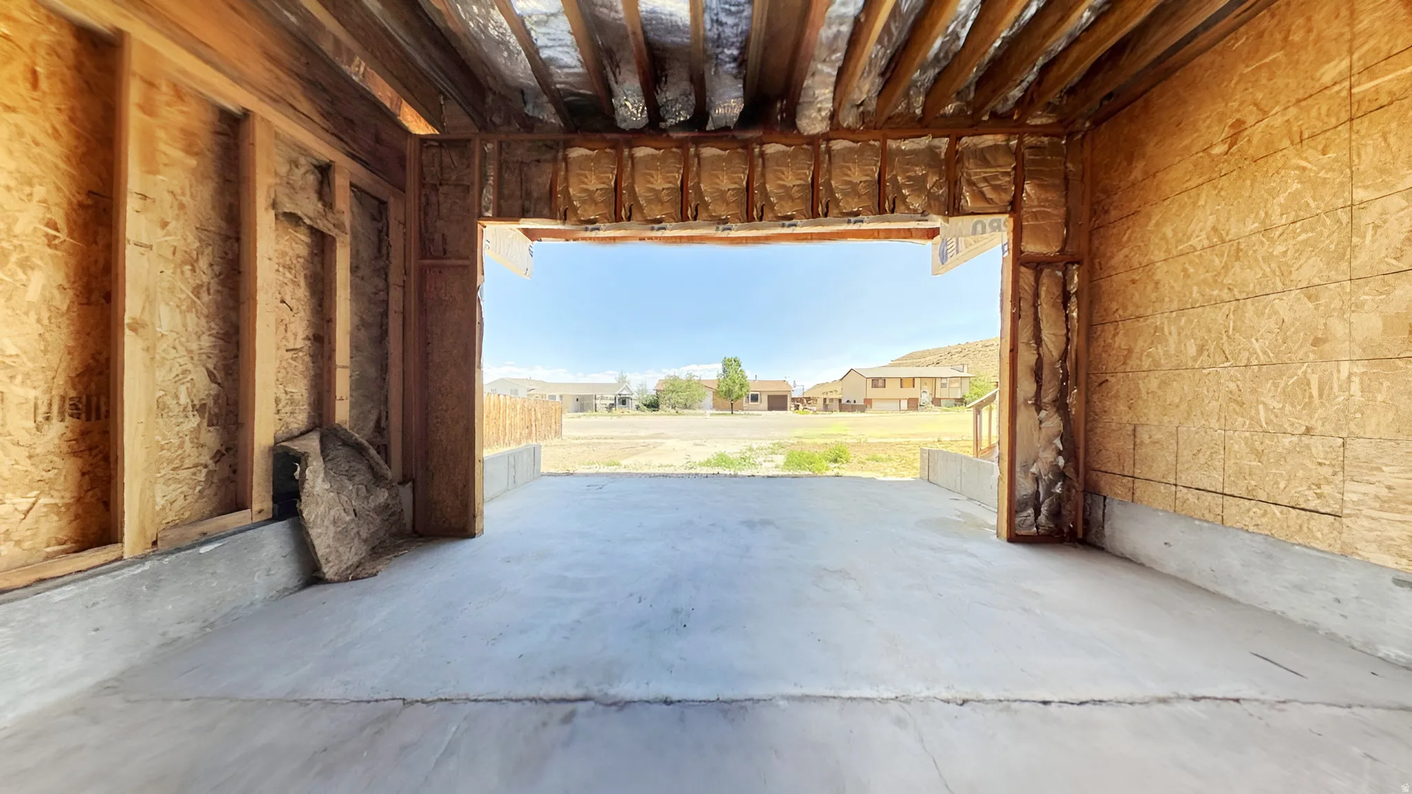 Unfinished interior space featuring exposed wood framing, concrete flooring, and visible insulation