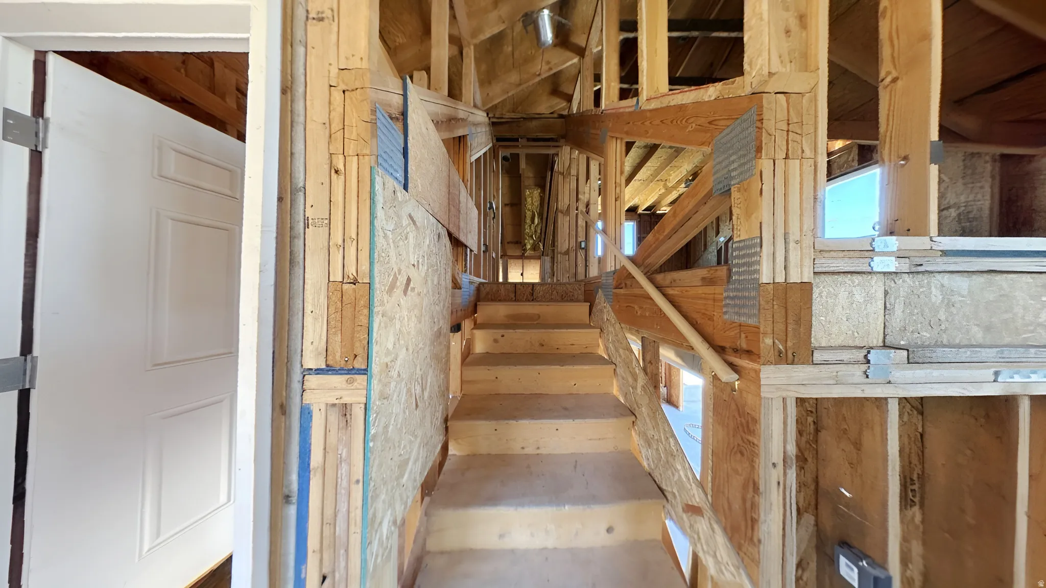 Partially constructed interior framing with exposed wood beams and subflooring