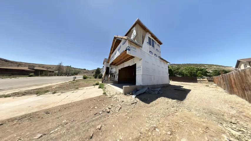 New construction framing featuring a garage opening, second-story dormer, and a sloped roofline