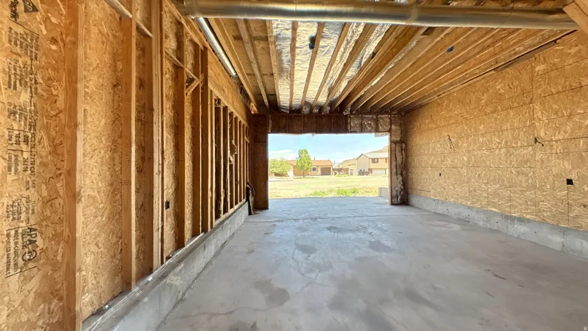 Unfinished garage space featuring a concrete floor, exposed wood framing, and oriented strand board sheathing