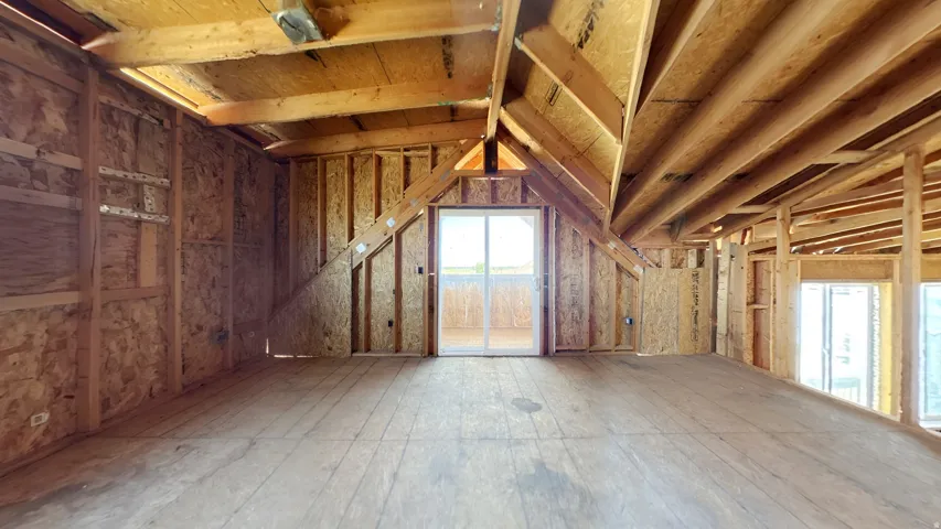 Spacious unfinished interior featuring exposed wood framing, plywood subflooring, and a sliding glass door