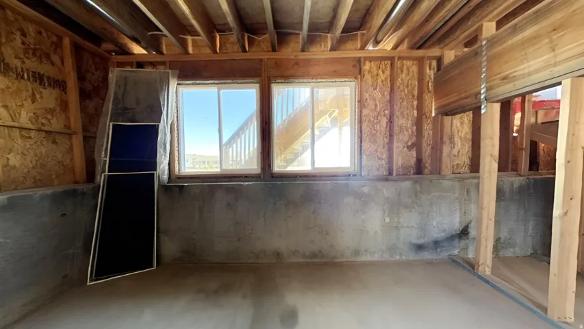 Unfinished interior space featuring exposed wooden ceiling joists and wall studs