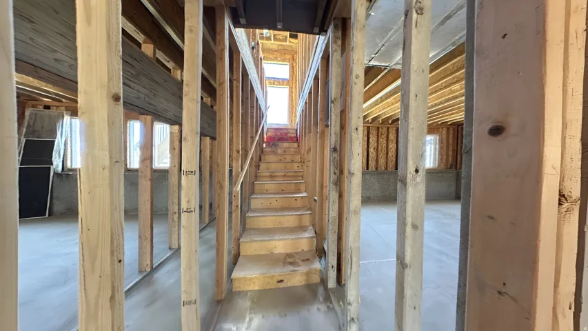 Framed interior structure featuring a central wooden staircase