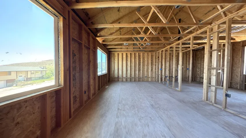 Unfinished interior space featuring exposed wood framing, an unfinished plywood subfloor, and two installed windows