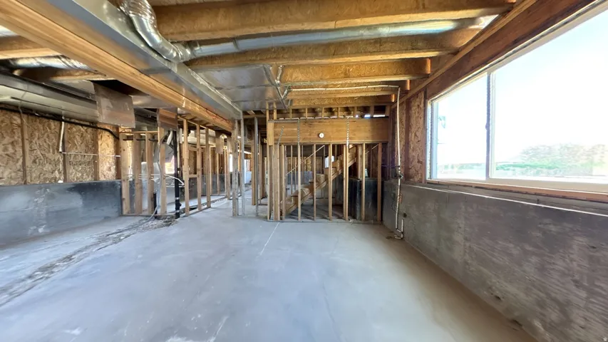 Unfinished interior space featuring exposed wood framing, concrete flooring, and a large window providing ample natural light