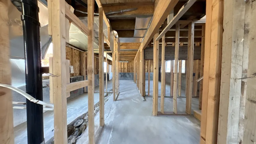 Interior framing with exposed wooden studs, concrete subfloor, visible plumbing, and electrical wiring
