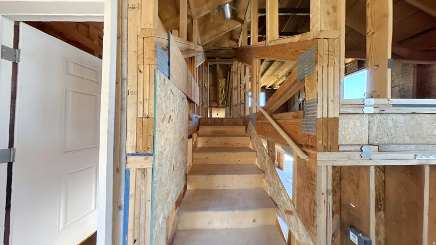 Partially constructed interior framing with exposed wood beams and subflooring